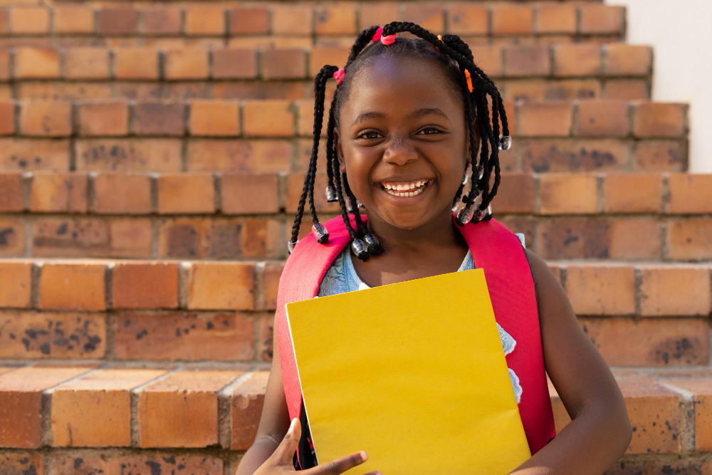 A pupil smiling on the school steps with her workbook