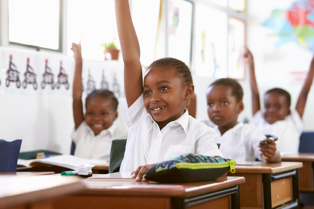 A Greenfield pupil answering a question with her hand raised at her desk